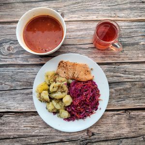 Zdjęcie przedstawia dietę podstawową:  Zupa pomidorowa z makaronem Ziemniaki młode z koperkiem gotowane Łosoś pieczony z przyprawami Surówka z czerwonej kapusty z natką pietruszki i słonecznikiem Kompot owocowy z jabłkami